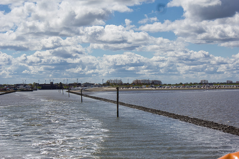 Langsam fährt die Fähre entlang des Leitdamms. Kueste Harlesiel mit Fährhafen und Strand