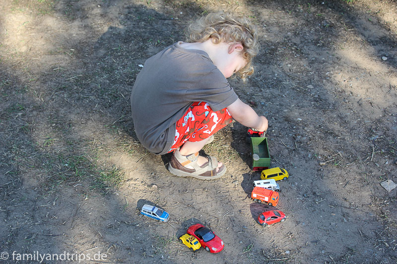 So versunken. Kind spielt mit den Autos auf Campingplatz.